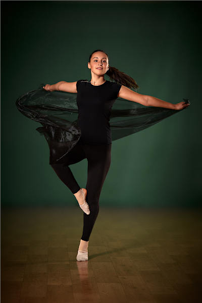 Девушка танцует в темном танцевальном костюме с юбкой